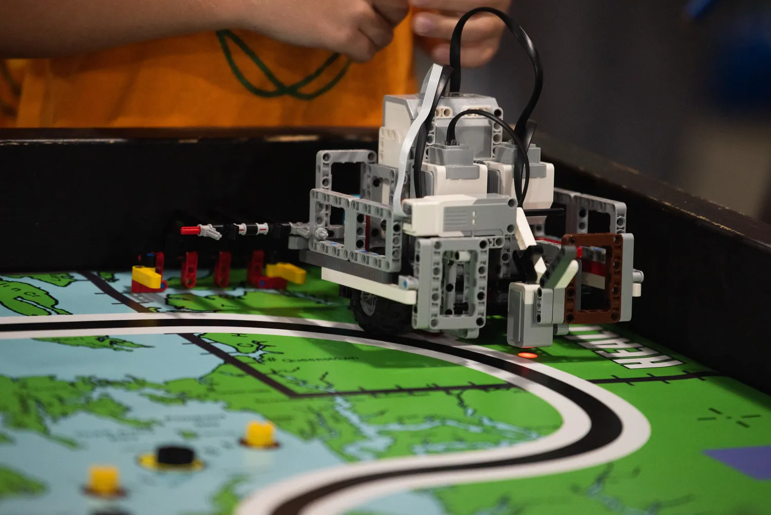 Students working with a programmable educational robot on a tabletop course.